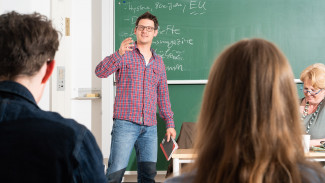 Studierender steht an der Tafel und erklärt anderen Studierenden etwas in einem Seminar