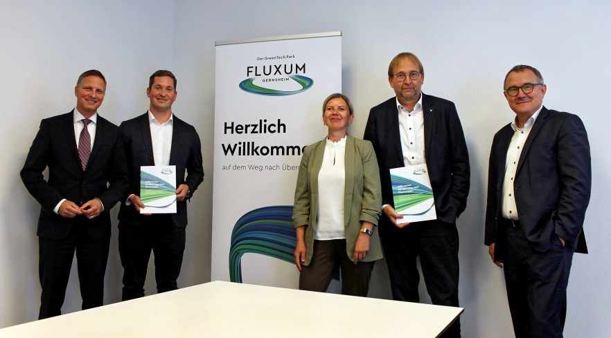 Fünf Personen stehen vor einem FLUXUM Rollup