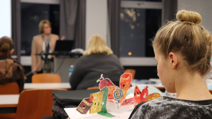 Eine junge Frau betrachtet während eines Vortrags ein Bilderbuch der 'Raupe Nimmersatt'. (Foto: Nadine Hehemann)