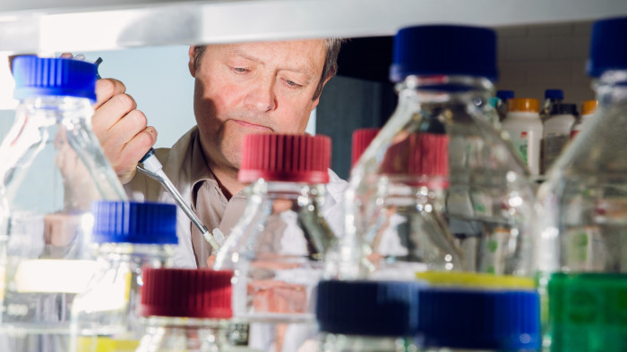 Professor Felix Hausch steht im Labor hinter Reagenzgläsern. Er appliziert etwas mit einer Pipette